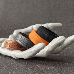 three white and orange rings sitting on top of each other in the shape of hands