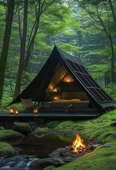 a tent in the middle of a forest with a fire pit and chairs around it