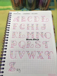 an open notebook with letters and numbers drawn on it next to some crayons