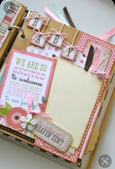 an open scrapbook with pink and green accents on it's cover, featuring the words we are so excited to welcome