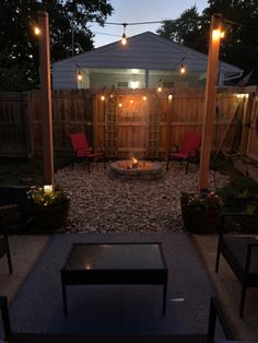 an outdoor patio with fire pit surrounded by chairs and lights on the side of it