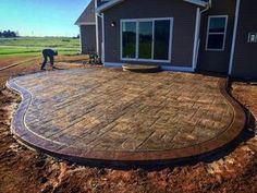 a patio being built in front of a house with a man working on the ground