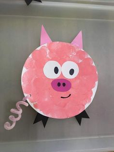 a paper plate with a pink pig face on it's side and black legs