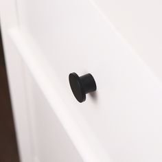 a black knob on the side of a white cabinet