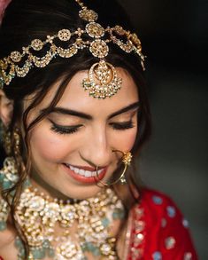 a woman in a red and gold outfit smiles while wearing a head piece with jewels on it