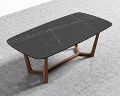 a black marble table with wooden legs on concrete flooring and white walls in the background