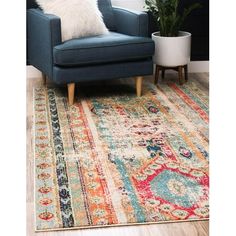 a blue chair sitting on top of a wooden floor next to a rug and potted plant