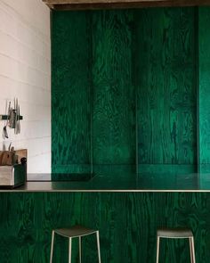 three stools are sitting in front of a green counter top with wood paneling