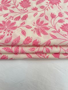 pink and white fabric with floral designs on it's edges, folded to the side