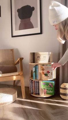 a woman in a white hat standing next to a stack of books on top of a wooden table