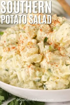 a white bowl filled with potato salad and garnished with parsley on the side