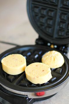 three waffles sitting on top of a black pancake maker next to each other