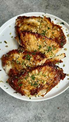 three pieces of chicken on a white plate with parmesan sprinkles