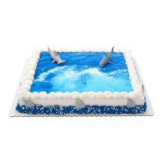 two dolphins jumping out of the water on top of a blue and white sheet cake