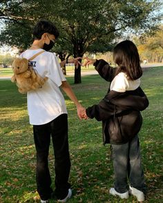 a boy and girl holding hands in the park