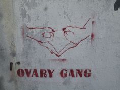 two hands making a heart shape with the words ovary gang painted on it