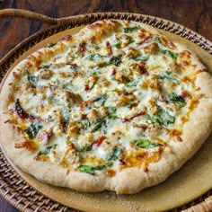 a pizza sitting on top of a wooden table next to a basket filled with food