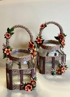 two glass jars with flowers on them sitting on a table