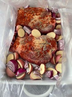 a piece of meat in a plastic bag with onions and other vegetables around it on a table