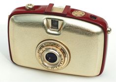 a red and gold camera sitting on top of a white table