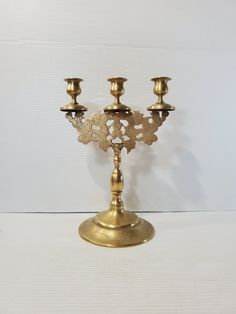 an ornate brass candelabra with four candles on the top and one candle holder in the middle