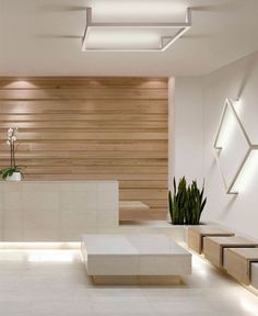 an empty room with white furniture and wood paneling on the wall, along with potted plants