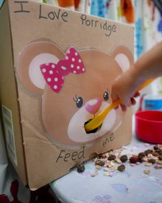 a child's hand holding a spoon in front of a cardboard box