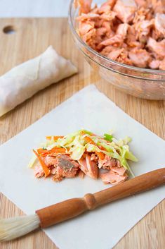 a wooden cutting board topped with food next to a bowl of meat and veggies