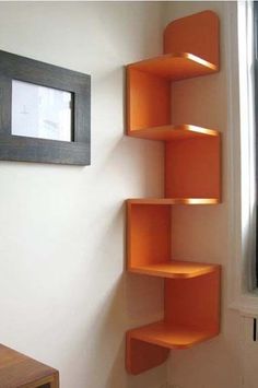 an orange shelf in the corner of a room next to a window with a framed picture on it