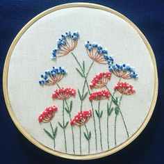 a close up of a embroidery on a white surface with red, white and blue flowers