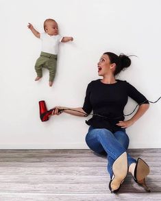 a woman sitting on the floor with a baby in front of her and an electric hair dryer behind her