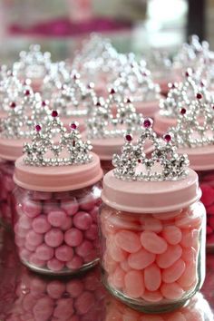 candy jars filled with pink and white candies, topped with tiara crowns on top