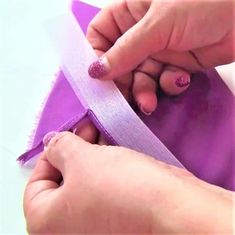 someone is cutting the edge of a purple ribbon