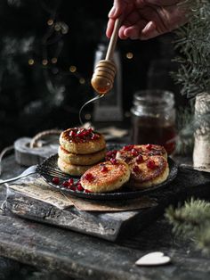 a person is spooning honey over some pancakes on a plate with cranberry sauce