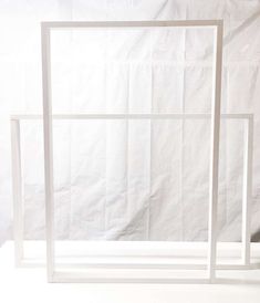 two white frames sitting next to each other on top of a table in front of a white backdrop