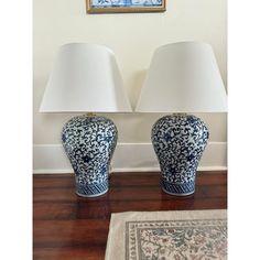 two blue and white vases sitting on top of a wooden floor next to lamps