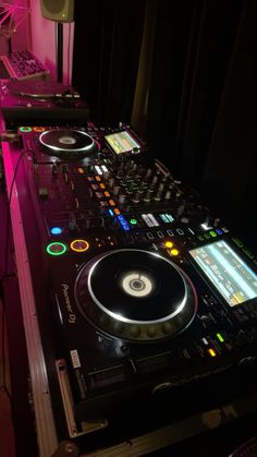 a dj's turntable in the dark with lights on and music equipment around it