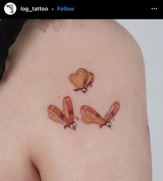 a woman's back with three tattoos on her left shoulder and two hearts in the middle