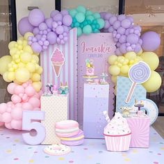 a table topped with lots of balloons and desserts next to a sign that says it's 5