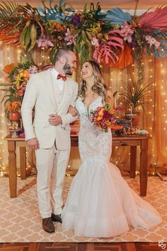 a bride and groom are standing in front of a floral backdrop at their wedding reception