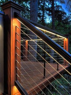 a wooden deck in the middle of a forest with metal railings and lights on it