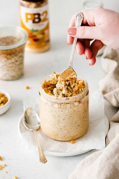 a person holding a spoon over a jar filled with oatmeal