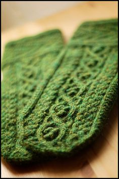 a close up of a pair of green knitted mitts