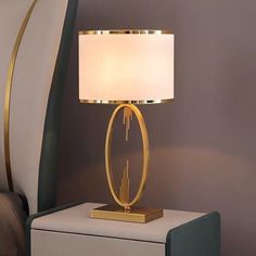 a lamp that is on top of a night stand in front of a purple wall