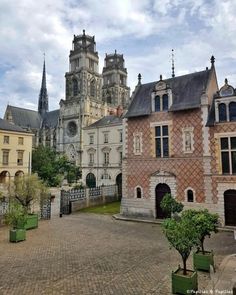 an old building with many windows and towers in the middle of a courtyard surrounded by trees