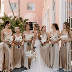 a group of women standing next to each other in front of a building with palm trees