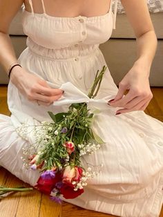 a woman sitting on the floor with flowers in her lap and wrapping it around her