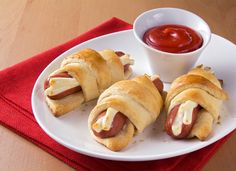 two hot dogs wrapped in bread on a plate with ketchup