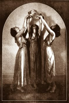 three women in long dresses are holding their hands on the back of each other's heads