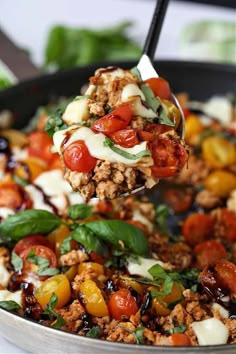 a spoon full of meat and vegetables being lifted from a skillet with cheese on top